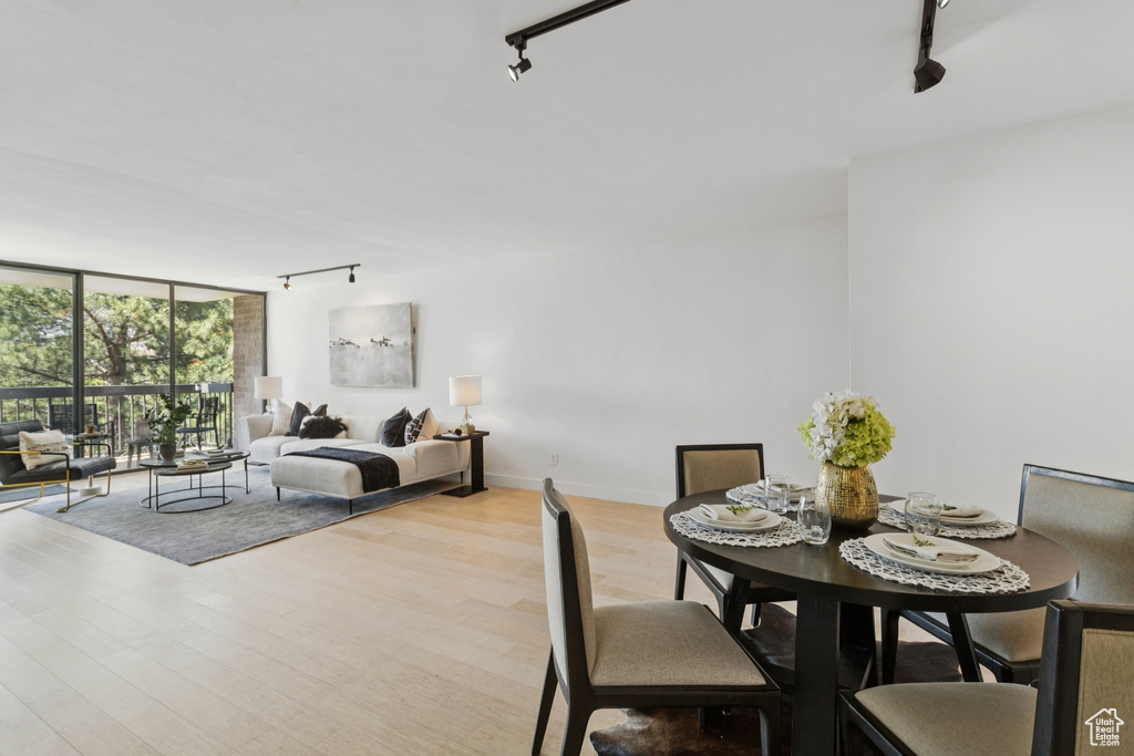 Dining space with track lighting, a wall of windows, and wood finished floors