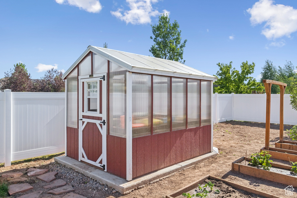View of greenhouse with a garden and a fenced backyard