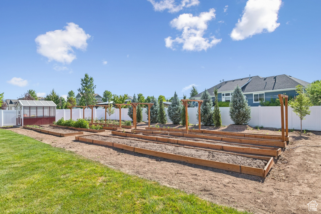 View of yard featuring a vegetable garden, a greenhouse, and an outdoor structure