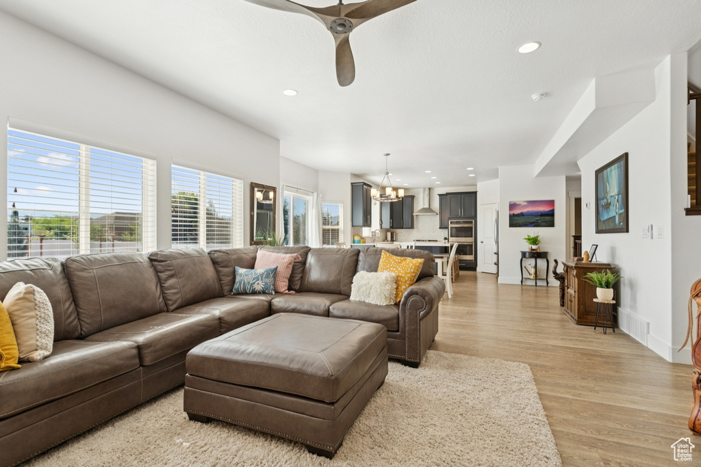 Living room featuring a chandelier, light wood-type flooring, recessed lighting, and ceiling fan