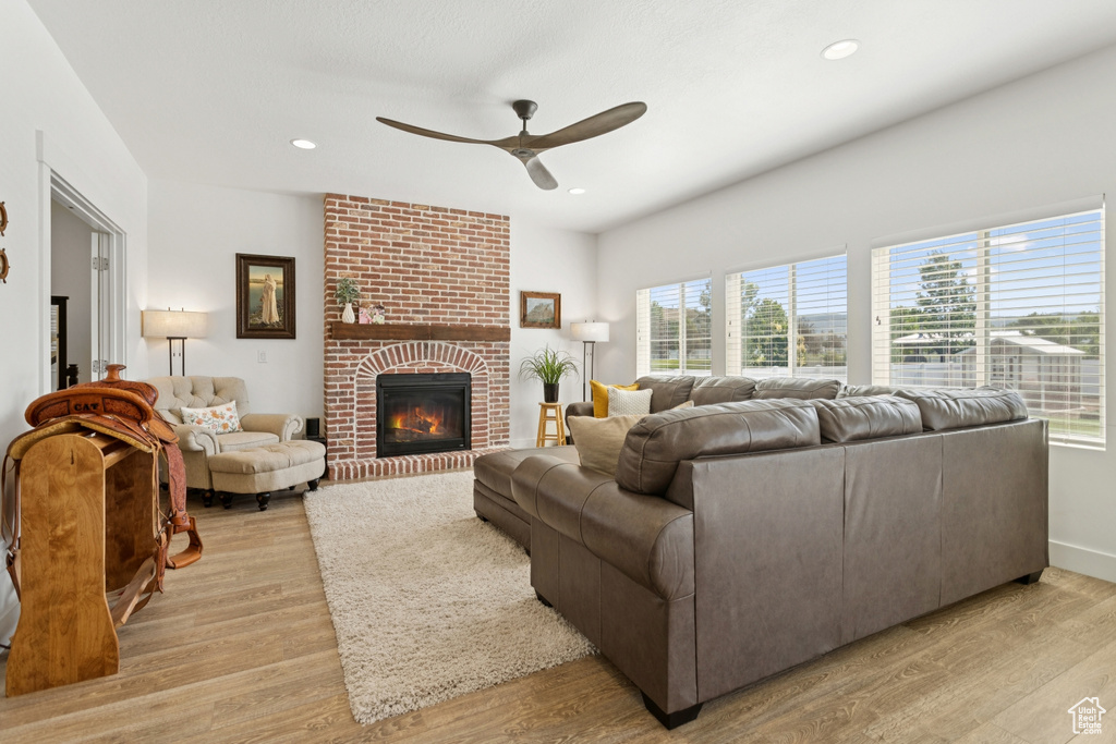 Living area featuring ceiling fan, plenty of natural light, light wood-style flooring, a fireplace, and recessed lighting