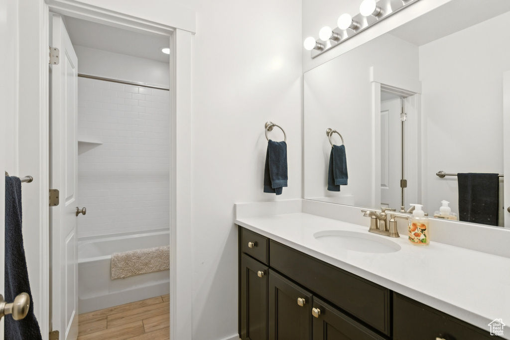 Full bath featuring vanity, wood finished floors, and tub / shower combination