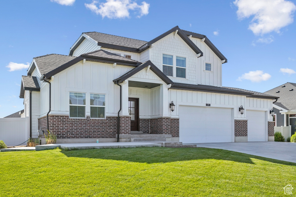Modern farmhouse style home featuring board and batten siding, driveway, brick siding, a garage, and a shingled roof