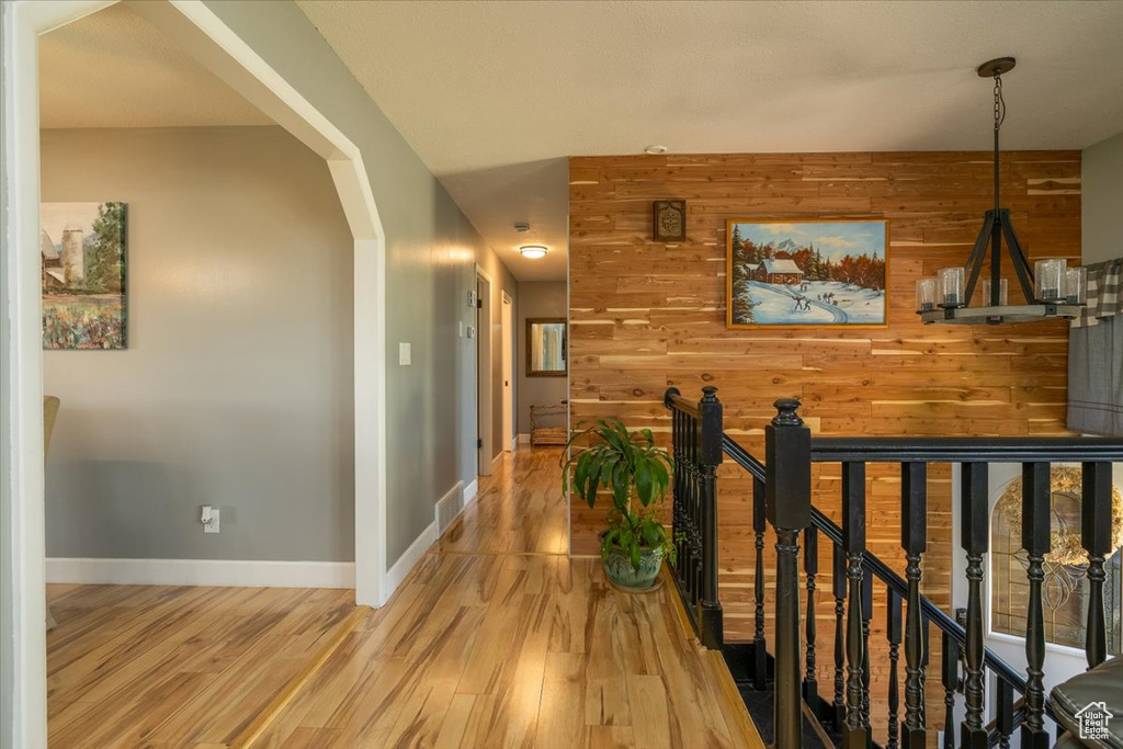 Hall with wooden walls, arched walkways, and light wood-style floors