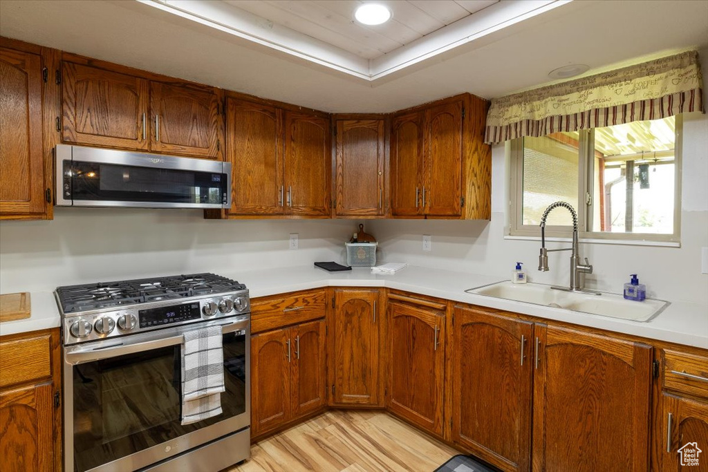 Kitchen with appliances with stainless steel finishes, light countertops, and brown cabinetry