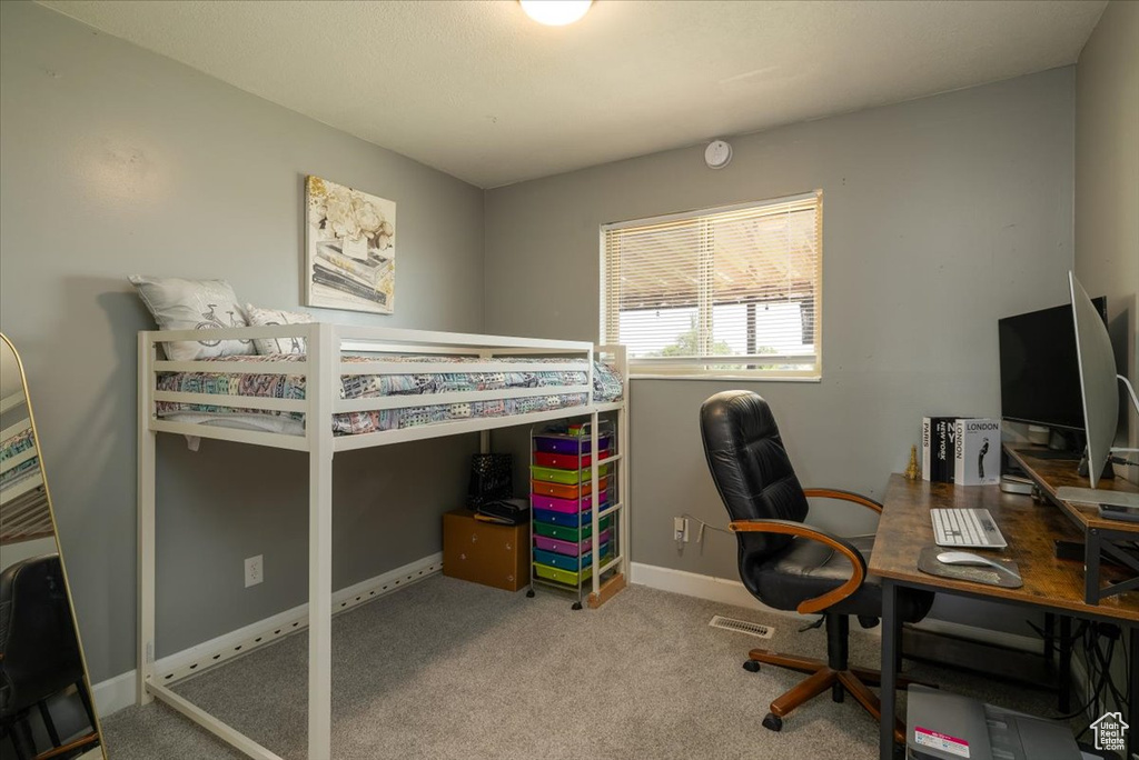 Carpeted bedroom with baseboards and a desk