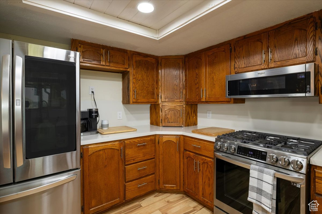 Kitchen with appliances with stainless steel finishes, light countertops, light wood-style floors, and brown cabinets