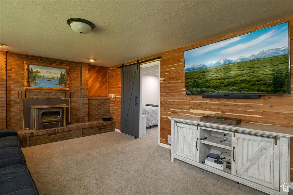 Unfurnished living room with a barn door, a textured ceiling, wooden walls, and carpet floors