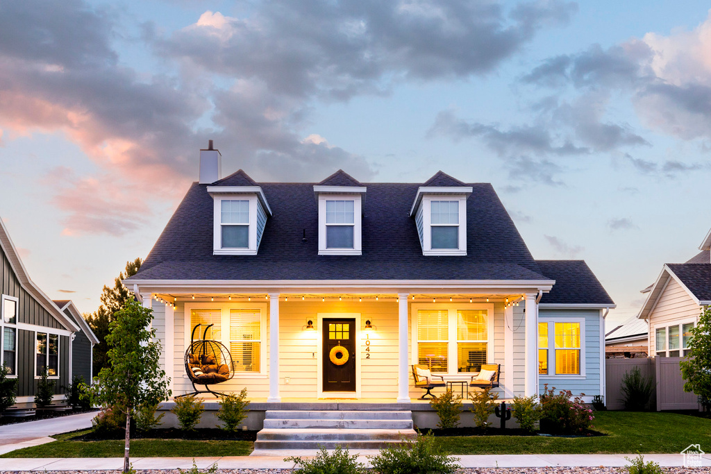 Cape cod home with covered porch, a chimney, and roof with shingles