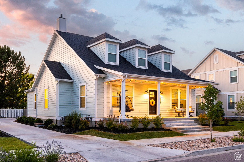 Cape cod home with a porch, a chimney, and a shingled roof