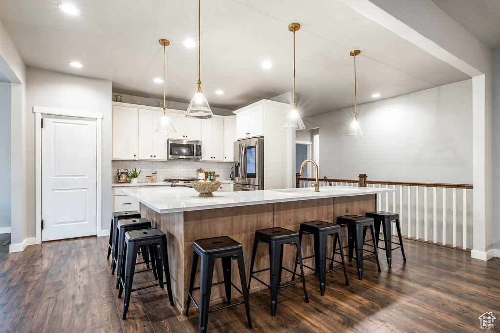 Kitchen featuring stainless steel appliances, dark wood finished floors, decorative backsplash, light countertops, and recessed lighting