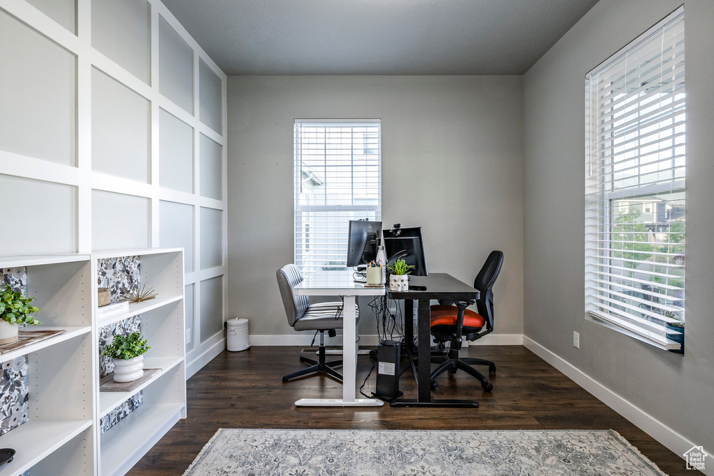 Office space with healthy amount of natural light and dark wood-style flooring