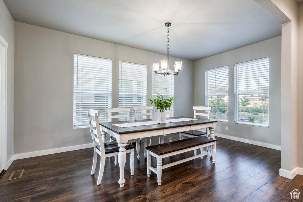 Dining space with a chandelier and dark wood-style flooring
