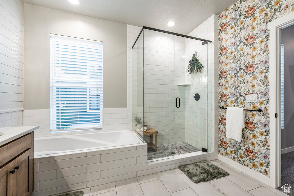 Full bath featuring a bath, tile patterned flooring, a stall shower, wallpapered walls, and vanity