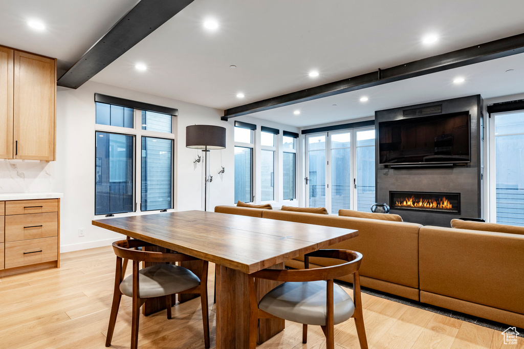 Dining space with beamed ceiling, light wood-type flooring, a large fireplace, and recessed lighting