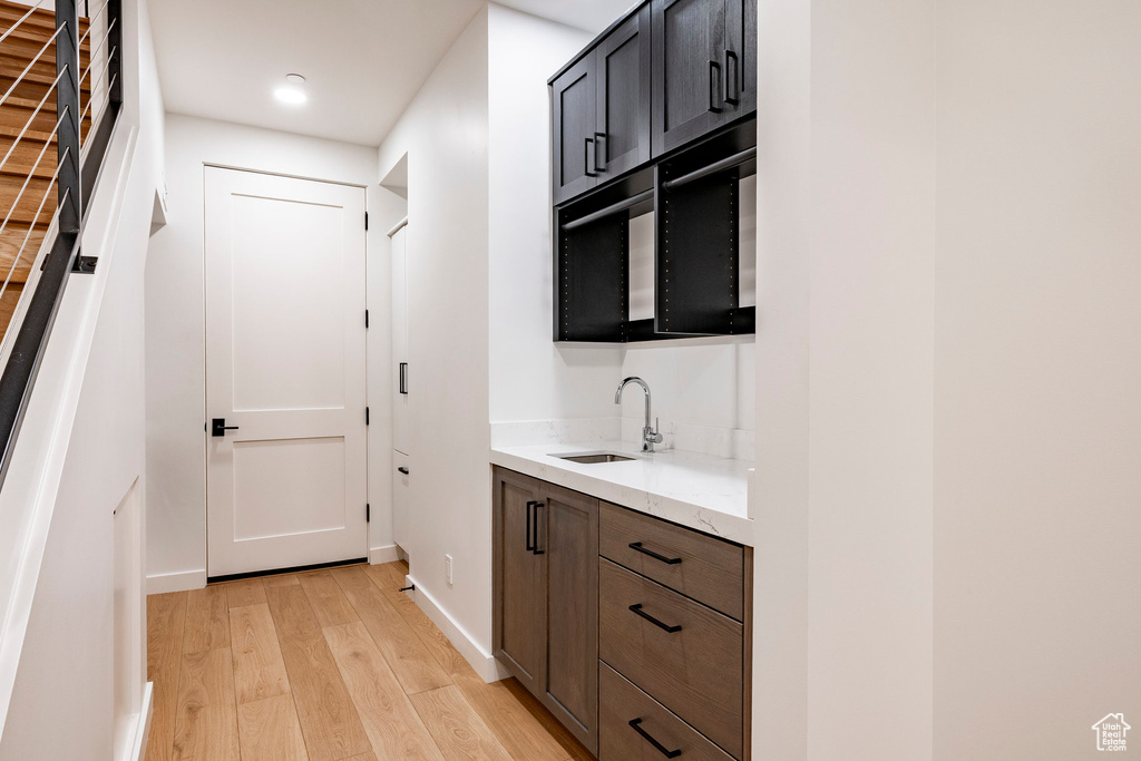 Indoor wet bar with light wood-style flooring, recessed lighting, and black microwave