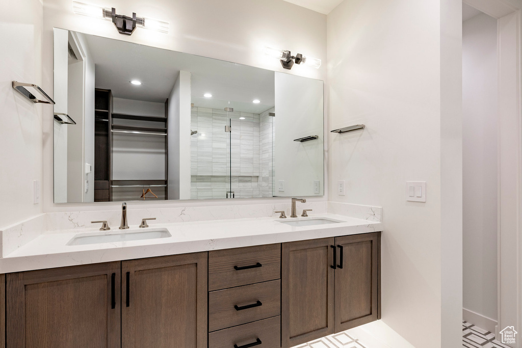 Bathroom featuring a stall shower, double vanity, and a walk in closet
