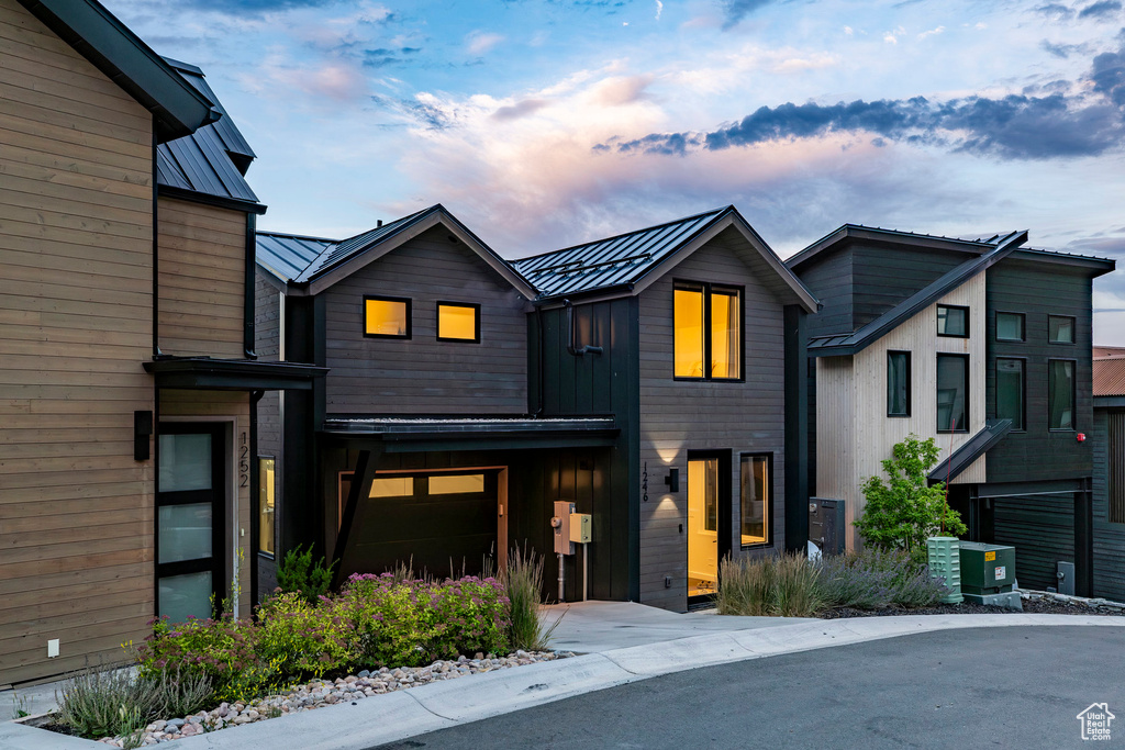 Modern home with a standing seam roof, a metal roof, and concrete driveway