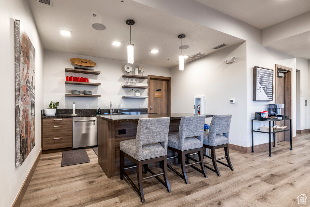 Kitchen with dishwasher, open shelves, light wood-type flooring, and a breakfast bar area