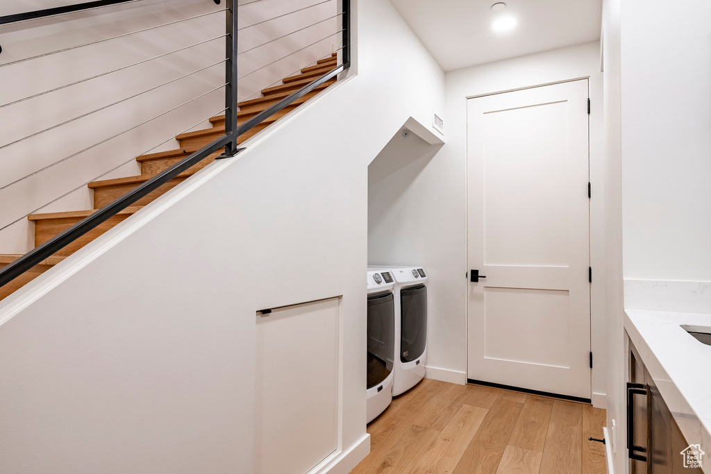 Laundry area with washing machine and dryer and light wood-type flooring