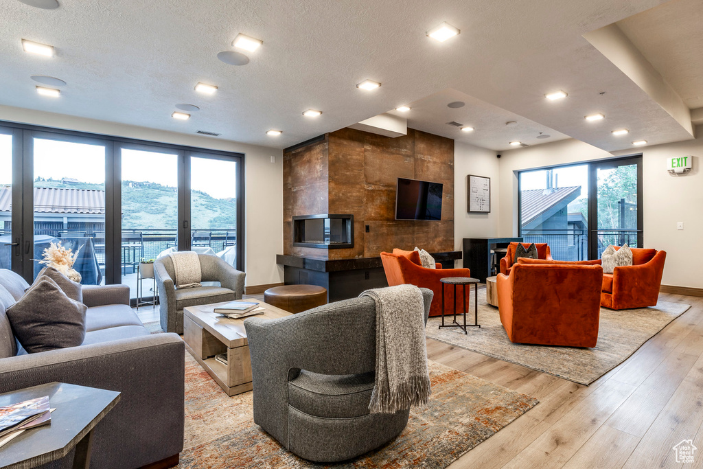 Living room featuring light wood finished floors, a textured ceiling, and recessed lighting
