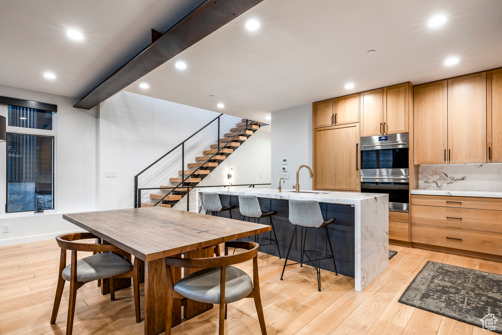 Kitchen featuring double oven, light wood-style flooring, light countertops, and recessed lighting