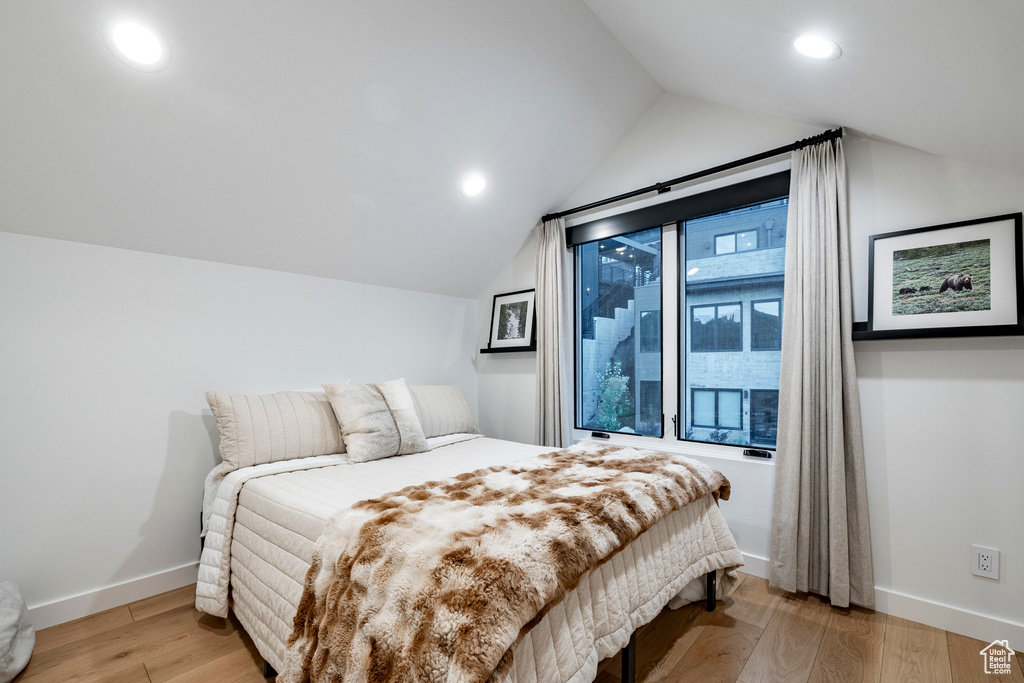 Bedroom with lofted ceiling, light wood-style flooring, and recessed lighting