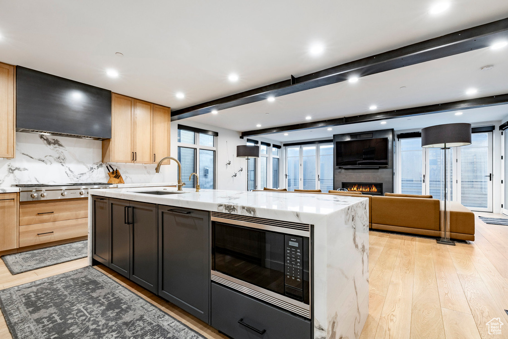 Kitchen featuring appliances with stainless steel finishes, ventilation hood, light wood-type flooring, open floor plan, and recessed lighting