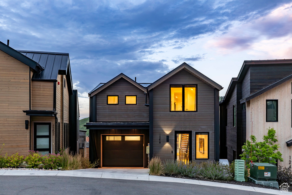 Modern home with an attached garage, a metal roof, and concrete driveway