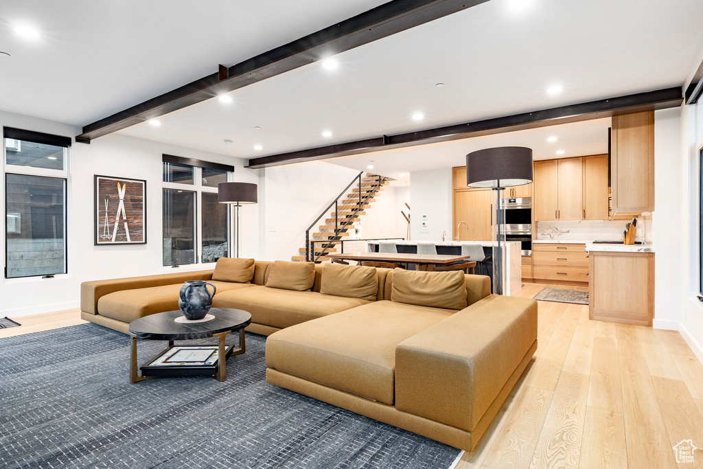 Living room with light wood-style flooring, beamed ceiling, stairway, and recessed lighting