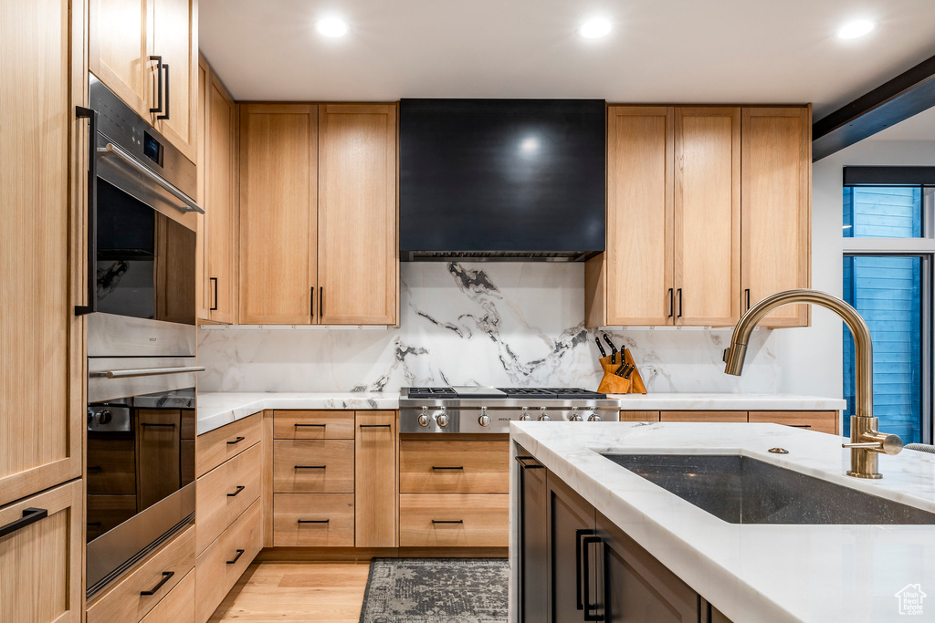 Kitchen with exhaust hood, appliances with stainless steel finishes, decorative backsplash, light brown cabinets, and recessed lighting
