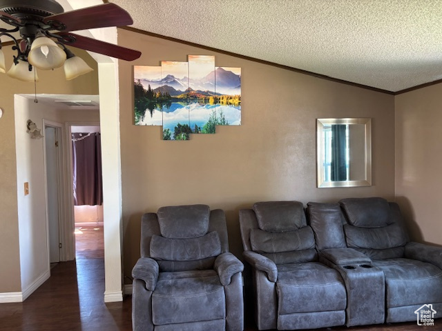 Living area with vaulted ceiling, a ceiling fan, a textured ceiling, ornamental molding, and dark wood-style flooring