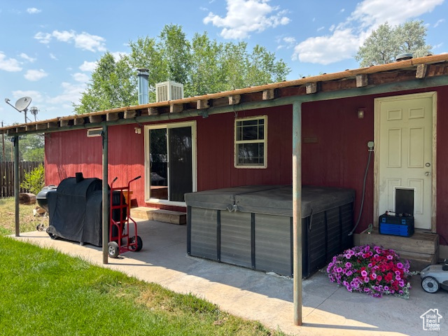 Back of property featuring a hot tub, a patio, and entry steps