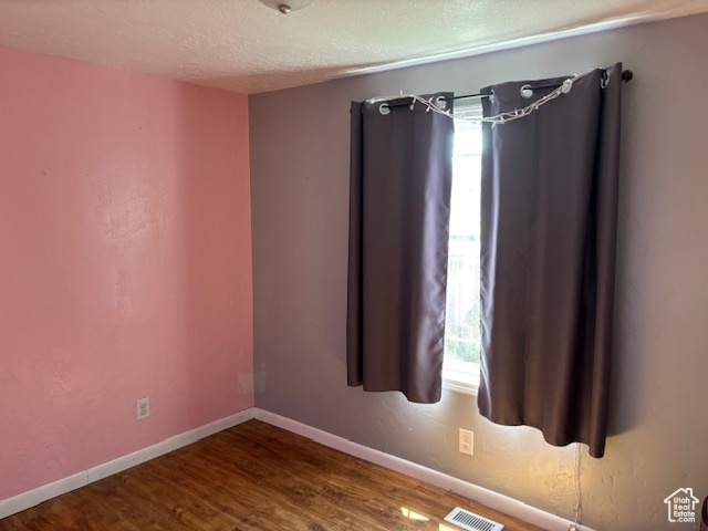 Unfurnished room with wood finished floors and a textured ceiling