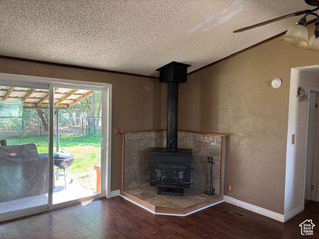 Detailed view of a textured ceiling, wood finished floors, a wood stove, a ceiling fan, and a smoke detector