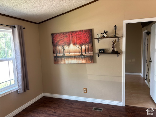 Spare room featuring ornamental molding, wood finished floors, a textured ceiling, and plenty of natural light