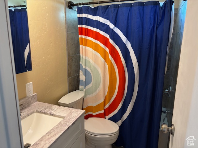 Bathroom featuring a textured wall, vanity, and curtained shower