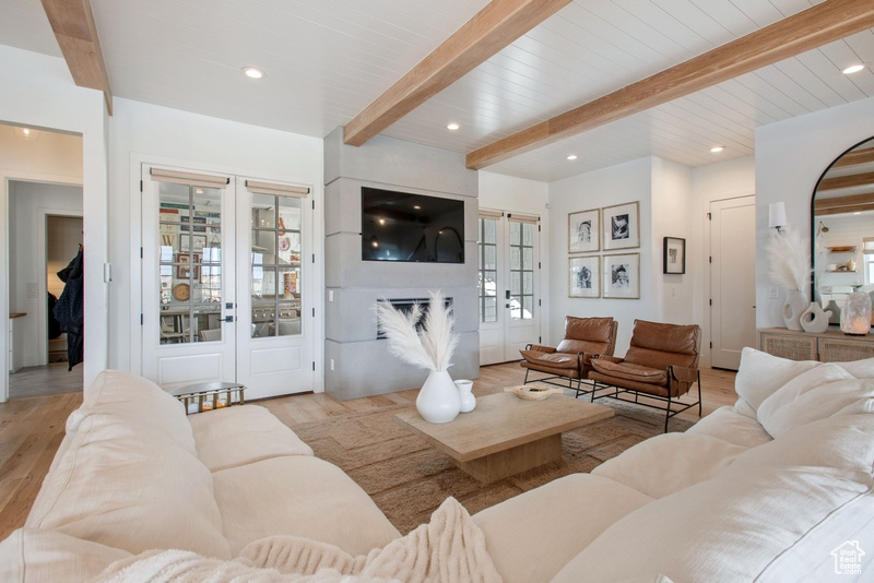 Living room with beam ceiling, light wood-type flooring, a glass covered fireplace, and recessed lighting