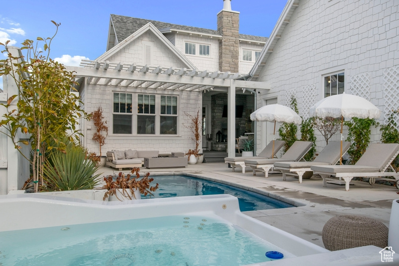 Back of house featuring a pergola, an outdoor hangout area, a patio, a swimming pool, and a chimney