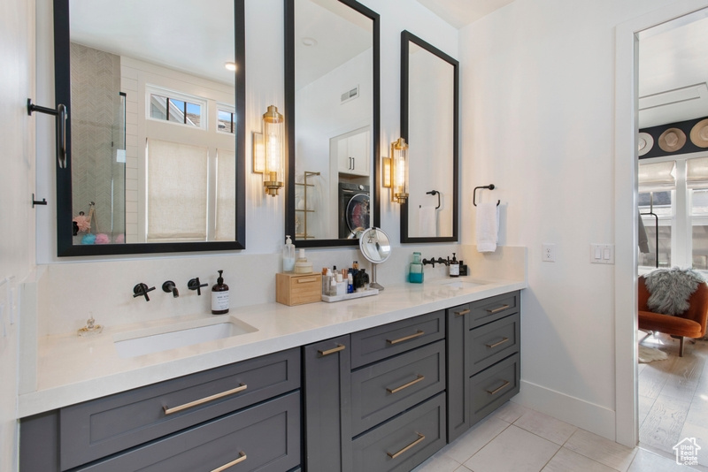 Bathroom with double vanity, tile patterned flooring, a shower, and washer / dryer