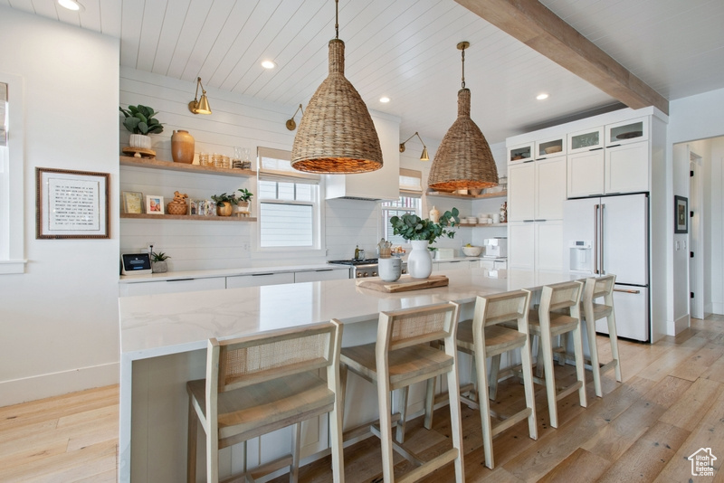 Kitchen featuring high end fridge, open shelves, light wood finished floors, a center island, and recessed lighting