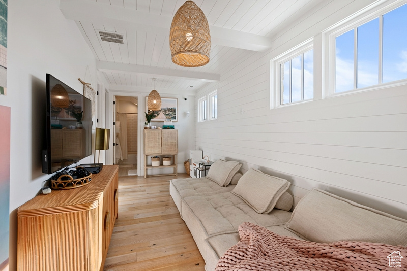 Living room featuring light wood-style flooring and a wooden ceiling with exposed beams