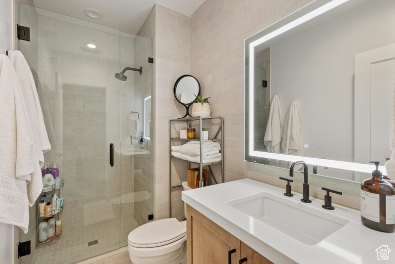 Full bath with tile walls, vanity, a shower stall, and tasteful backsplash