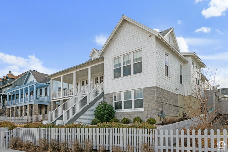 View of side of property with stone siding, stairs, and covered porch