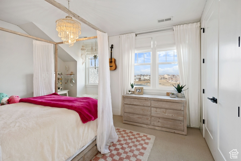 Bedroom with light carpet and a chandelier