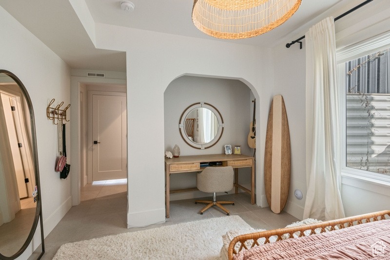 Bedroom with arched walkways and light tile patterned floors