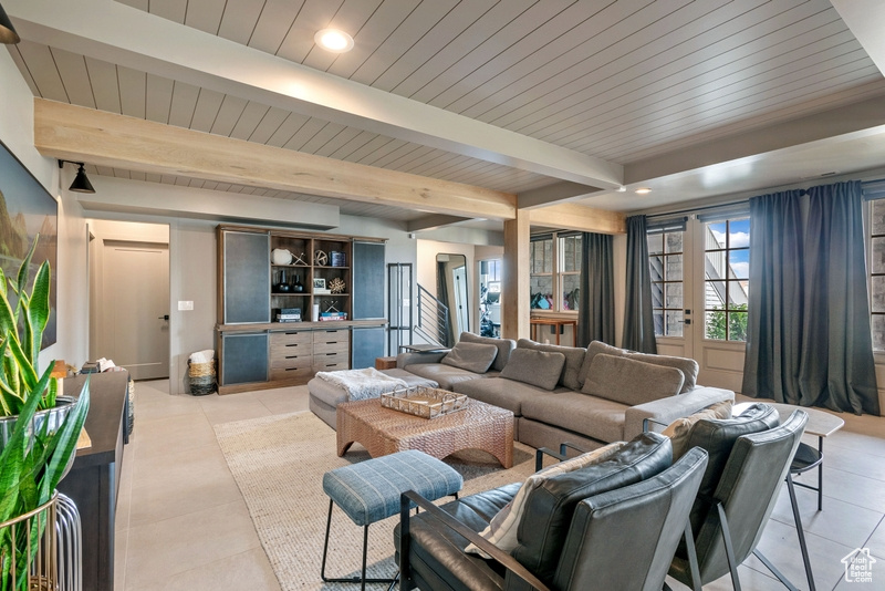 Living area with light tile patterned floors, a wood ceiling with exposed beams, and recessed lighting