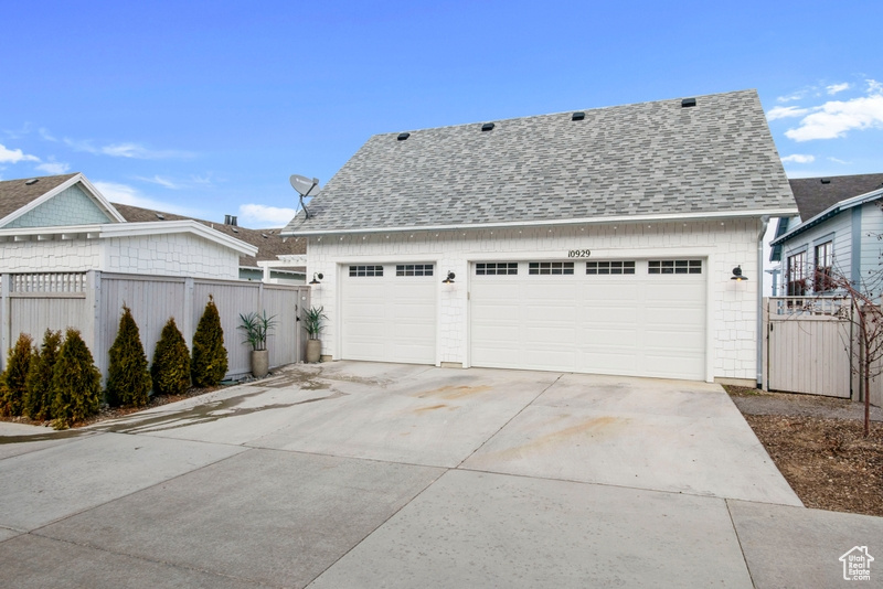 View of front of home with a shingled roof, concrete driveway, and a garage