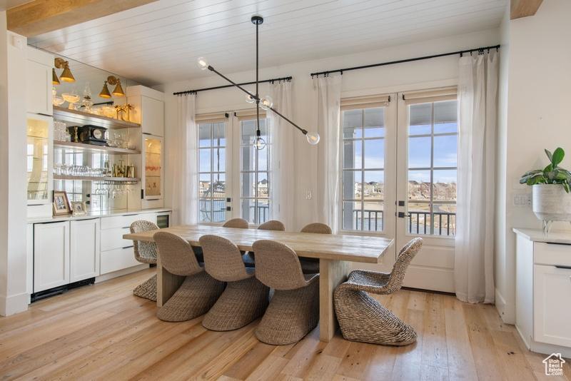 Dining room with light wood-style floors, bar, and french doors