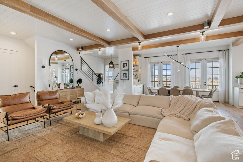 Living area with stairway, beamed ceiling, recessed lighting, and light wood finished floors
